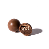 Dos Bombones de chocolate Crocanti crujientes redondos de ChocolateSI colocados sobre un fondo blanco, uno de ellos parcialmente cortado para revelar un interior cremoso y crujiente de leche y arroz inflado.
