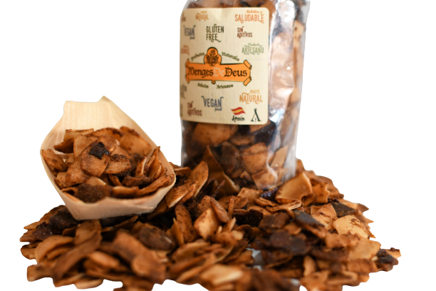 Un tarro de cristal con la etiqueta "Menges de Deus - Alicante - Cerdá, 104. 03009 Alicante" lleno de Coco Laminado Garrapiñados 1kg, con trocitos de coco tostado esparcidos y algunos en un pequeño cuenco de bambú.