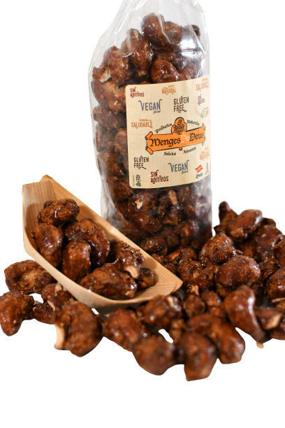 Una bolsa de 1 kg de Anarcados Garrapiñados de Menges de Deus (Alicante), etiquetados como veganos y sin gluten, con resaltes nutricionales y algunos racimos de frutos secos en un cacito de madera delante.