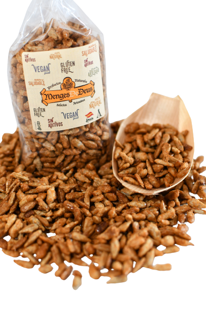 Una bolsa de plástico transparente de Pipas de Girasol Garrapiñadas 1kg de Menges de Deus, Alicante, etiquetadas como sin gluten y veganas, con snacks derramados cerca de un cucharón de madera sobre blanco. El envase destaca la información nutricional para un picoteo consciente.