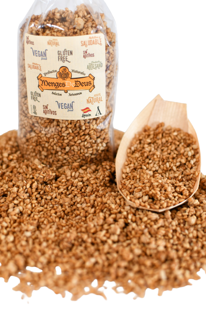 Una bolsa transparente con la etiqueta "Sésamo Garrapiñado 1kg" de Menges de Deus - Alicante - Cerdá, 104. 03009 Alicante contiene cereal inflado y semillas de sésamo, con cereal extra esparcido y un cacito de madera que contiene parte del mismo.