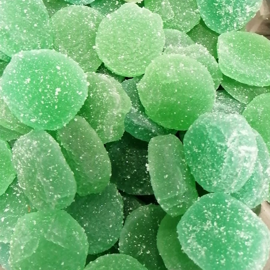 Un primer plano de Gominola de Manzana Natural 1kg de Menges de Deus (Alicante) muestra varias gominolas veganas redondas, verdes, recubiertas de azúcar y elaboradas con ingredientes naturales.