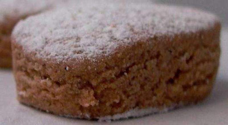 Primer plano de un Polvorón de Almendra ecológico de 200 g El Abuelo de Jijona S.A. en forma de corazón, espolvoreado con azúcar glas y apoyado sobre una superficie ligera.