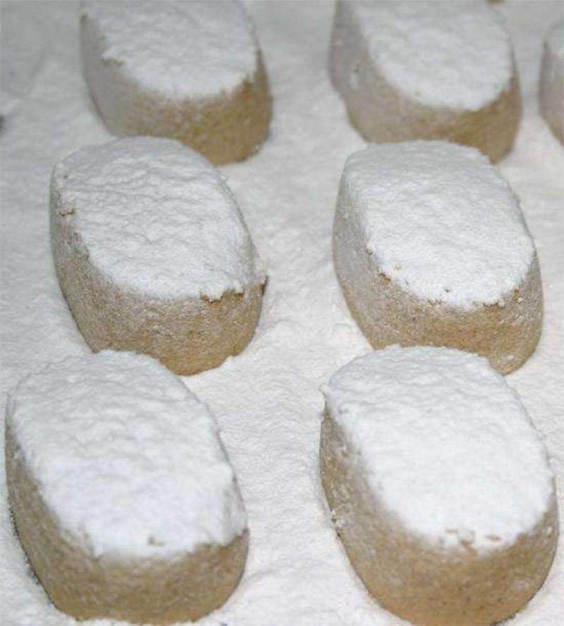 Sobre una superficie espolvoreada de azúcar en polvo se disponen varios Polvorones de Almendra ecológicos El Abuelo (200 g, Jijona S.A.), cada uno de ellos con forma ovalada y recubiertos de más azúcar en polvo.